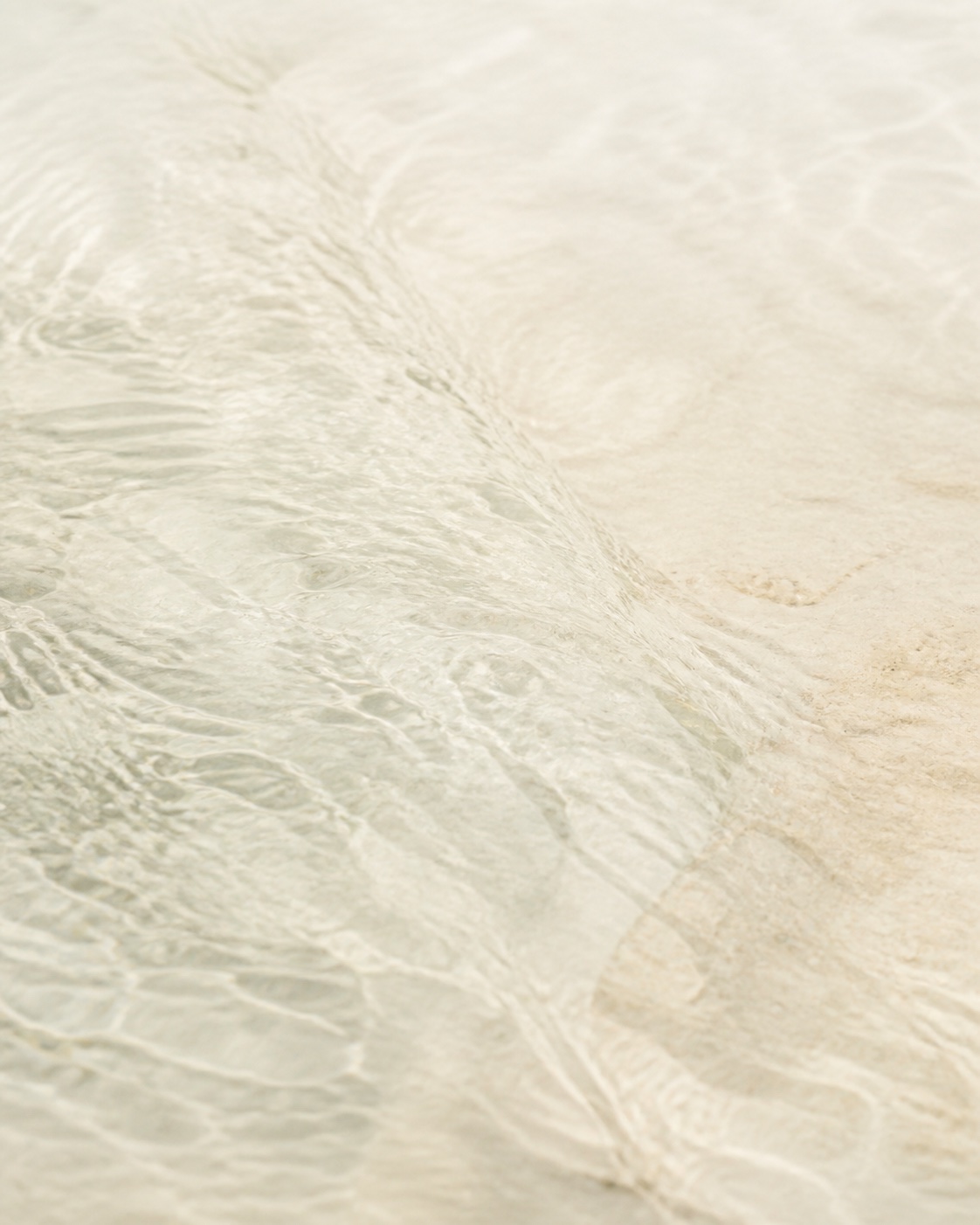 Clear shallow water moving across pale limestone