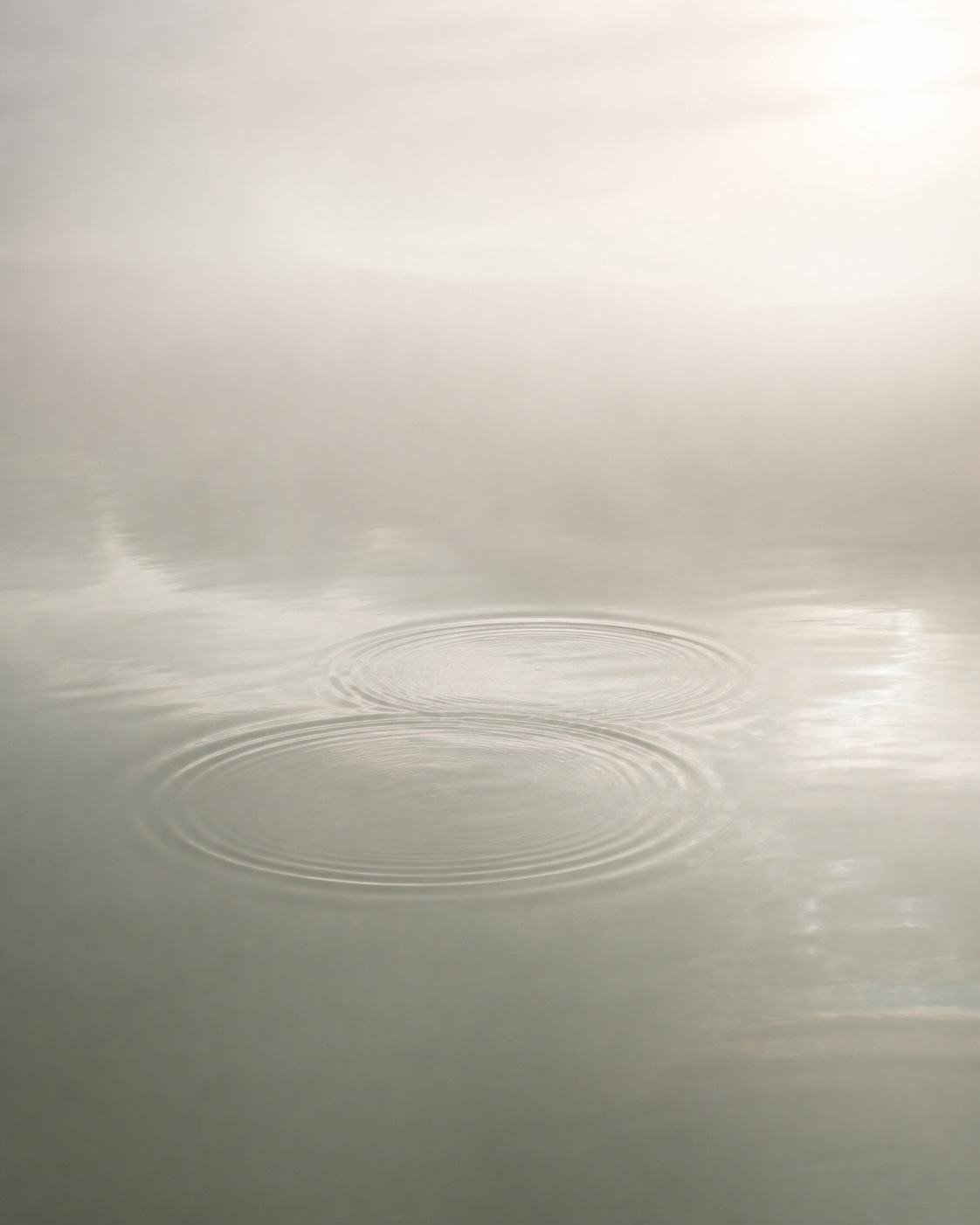 Two soft ripples overlapping on a calm water surface